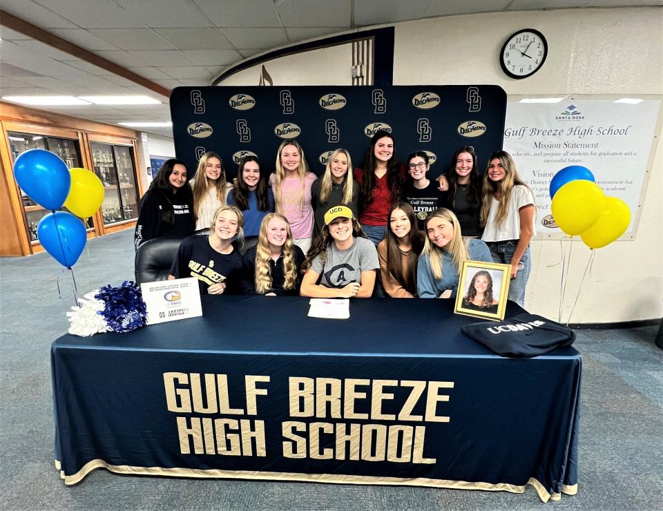 Gulf Breeze senior volleyball player Dixie Farish (bottom row center) is joined by her teammates after signing her letter of intent to play beach volleyball at UC-Davis during a ceremony on Wednesday, Nov. 9, 2022 from Gulf Breeze High School.