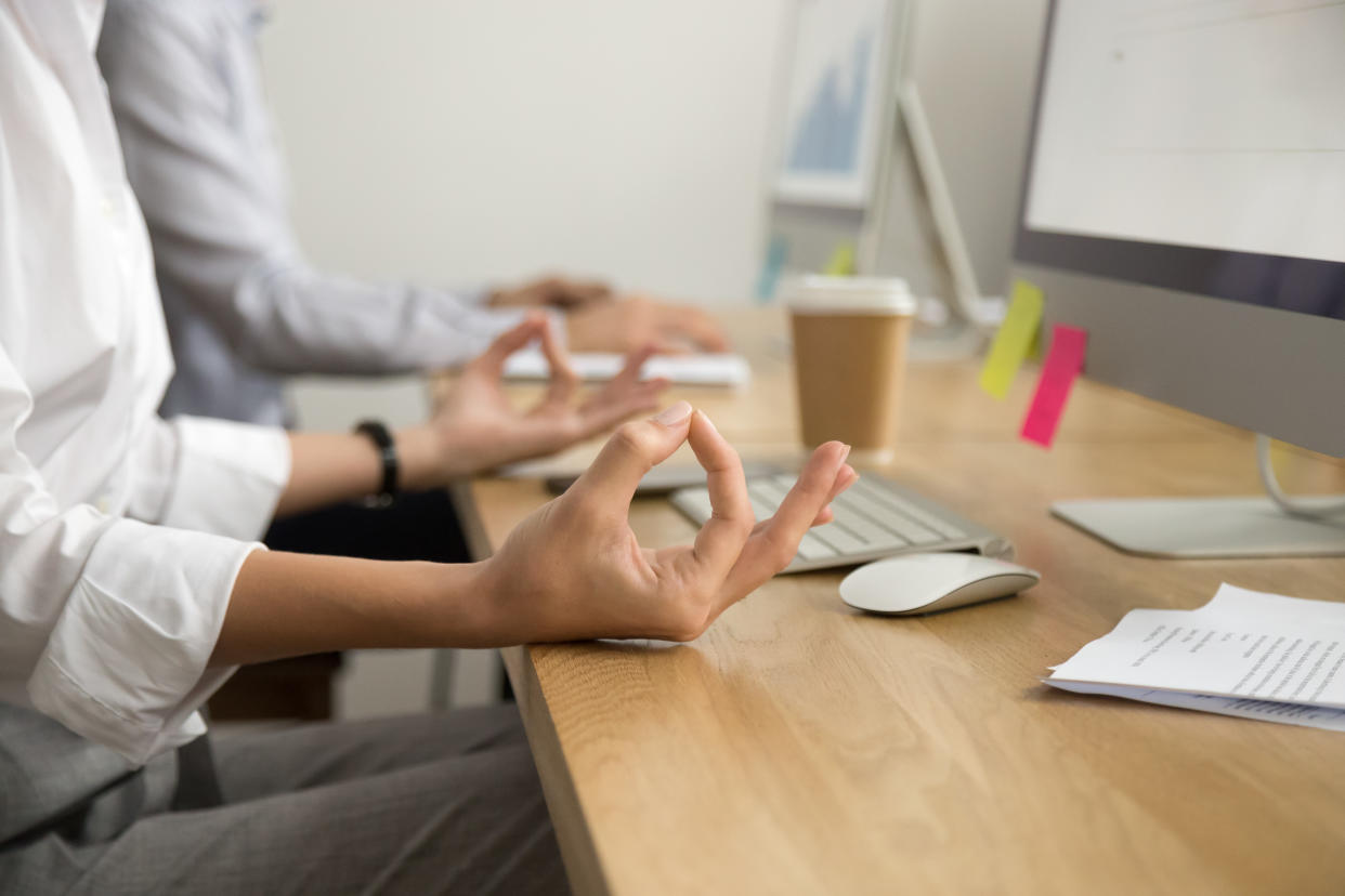 Office yoga for relaxation or concentration concept, calm businesswoman meditating at work, peaceful mindful employee practicing exercises at workplace, focus on female hands in mudra, close up view