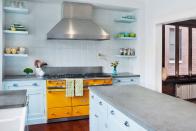 <p>Baby blue cabinets, floating shelves and tin tile backsplash look all the more soft and serene next to a marigold range in this space by <a rel="nofollow noopener" href="https://designers.elledecor.com/architects/randall-architects-inc" target="_blank" data-ylk="slk:Randall Architects;elm:context_link;itc:0;sec:content-canvas" class="link ">Randall Architects</a>.</p>