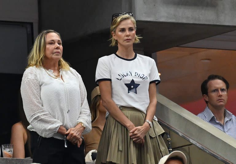 Charlize Theron, vistiendo una remera de Christian Dior, la casa de moda a la que representa hace años en las publicidades del perfume J'Adore, junto a sus mamá Gerda en el partido que disputaron el sábado Coco Gauff y Aryna Sabalenka