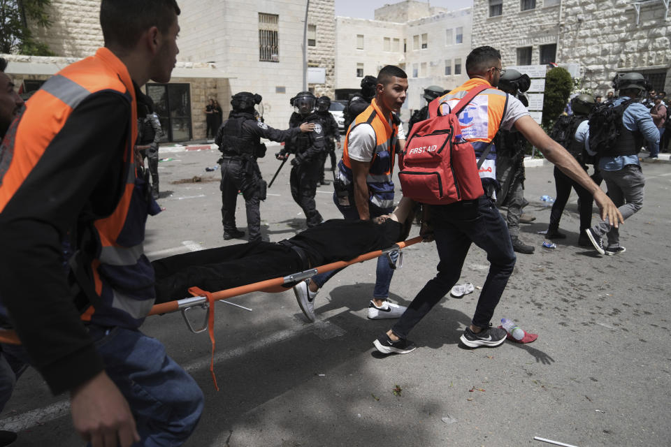 Palestinian medics evacuate a mourner wounded during clashes when Israeli police confronted people gathered as slain Al Jazeera veteran journalist Shireen Abu Akleh was transferred to her funeral before going to to her final resting place, in east Jerusalem, Friday, May 13, 2022. Abu Akleh, a Palestinian-American reporter who covered the Mideast conflict for more than 25 years, was shot dead Wednesday during an Israeli military raid in the West Bank town of Jenin.(AP Photo/Mahmoud Illean)