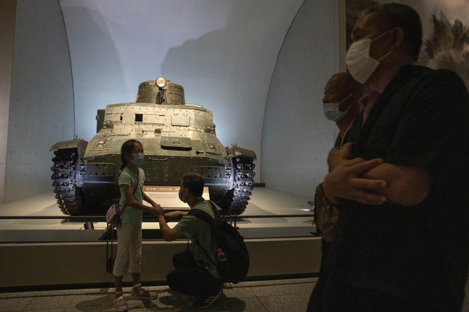 A man and child stand near a Japanese tank captured after the War of Resistance against Japanese Aggression at the military museum in Beijing on Thursday, Sept. 3, 2020. China on Thursday commemorated the 75th anniversary of the end of World War II in the Pacific, during which it endured a brutal invasion and occupation of much of its territory by Japan. (AP Photo/Ng Han Guan)