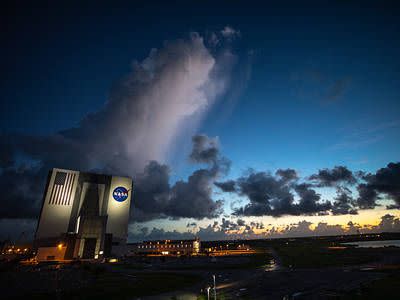An early sunrise view of the iconic Vehicle Assembly Building (VAB) at NASA's Kennedy Space Center in Florida on July 25, 2020. Repainting of the NASA meatball and American flag recently was completed on the 525-foot tall facility. Inside the VAB, 10 new work platforms, 20 platform halves altogether, have been installed in High Bay 3 for the agency's Space Launch System (SLS) rocket and Orion spacecraft. Exploration Ground Systems is overseeing upgrades to the VAB.