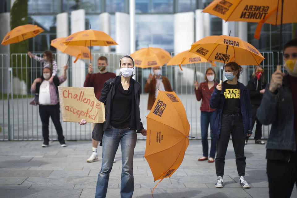 Activists of the Generation-Foundation hold symbolic rescue umbrellas in their hands during a protest in front of the chancellery in Berlin, Germany, Thursday, May 28, 2020. The Generation-Foundation is focusing on climate change and social justice and demand a change of the system for the further generations. The inscriptions on the umbrellas read: 'Generation Rescue Umbrella' - 'Climate Justice Democracy'. (AP Photo/Markus Schreiber)