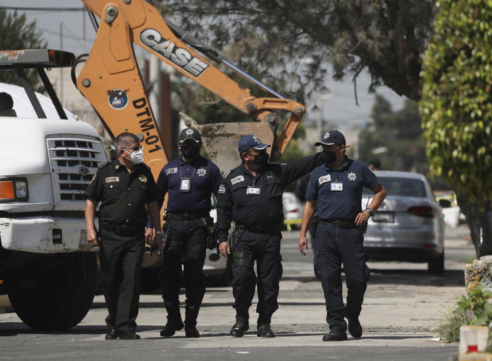 Police walk outside the house where bones were found under the floor in the Atizapan municipality of the State of Mexico, Thursday, May 20, 2021. Police have turned up bones and other evidence under the floor of the house where a man was arrested for allegedly stabbing a woman to death and hacking up her body. (AP Photo/Fernando Llano)