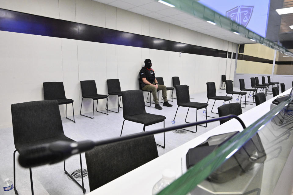 A policeman sits inside the box prior to the reading of the sentences during the trial regarding the attacks at a Brussels metro station and the city's airport at the Justitia building in Brussels, Friday, Sept. 15, 2023. The morning rush hour attacks at Belgium's main airport and on the central commuter line took place on March 22, 2016, which killed 32 people, and nearly 900 others were wounded or suffered mental trauma. (John Thys, Pool Photo via AP)