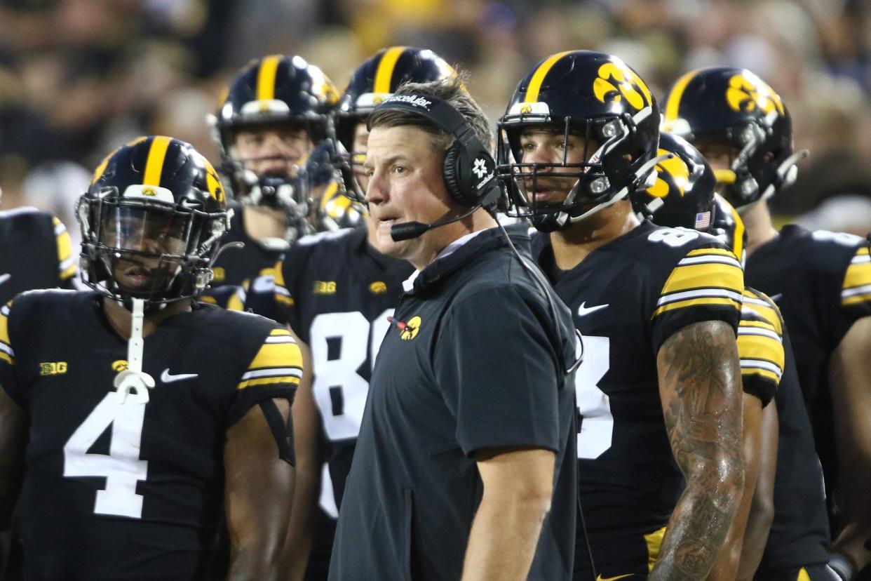 Ferentz in headset grimacing with the players behind him in uniform, all looking at the field