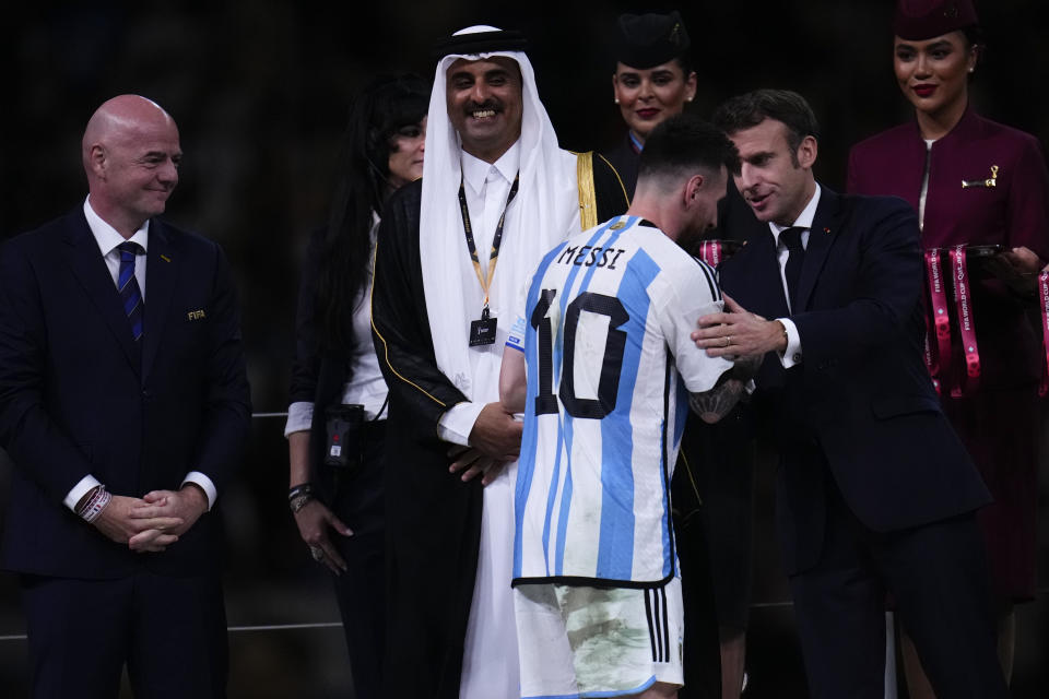 Argentina's Lionel Messi is congratulated by French President Emmanuel Macron as FIFA President Gianni Infantino and The Emir of Qatar Sheikh Tamim bin Hamad Al Thani look on, after winning the World Cup final soccer match between Argentina and France at the Lusail Stadium in Lusail, Qatar, Sunday, Dec.18, 2022. (AP Photo/Manu Fernandez)