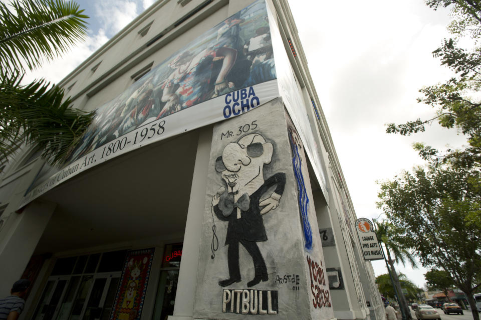 This May 1, 2014 photo shows a caricature of Cuban–American recording artist Pitbull on the side of the side of building along Calle Ocho (Eighth Street) in Miami's Little Havana. Once a refuge for Cuban exiles rekindling the tastes and sounds a lost home, today Miami’s Little Havana is a mosaic of cultures and a popular tourist destination. (AP Photo/J Pat Carter)