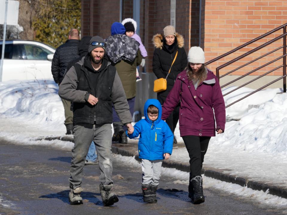 A couple escorts a child from a daycare centre after a city bus crashed into the facility in Laval, Quebec, Wednesday, Feb.8, 2023 (AP)