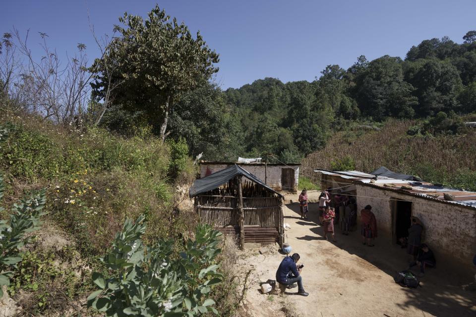 Victor Manuel Mateo Tiniguar, the brother of Salvador Mateo Tiniguar, sits on a footstool checking his cellphone messages outside his home in Chepol, in the western highlands of Guatemala, Saturday, Dec. 11, 2021. Salvador Mateo Tiniguar, who was migrating to the United States, was traveling on the truck that crashed in Mexico that killed 55 migrants. His family does not know what happened to him as they wait for information from Mexican authorities who have released a list of seven seriously injured unidentified people. (AP Photo/Moises Castillo)