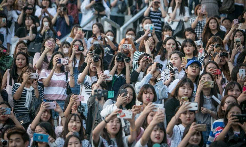 South Korean fans of K-Pop boy band Exo try to catch a glimpse of them in a parking lot.