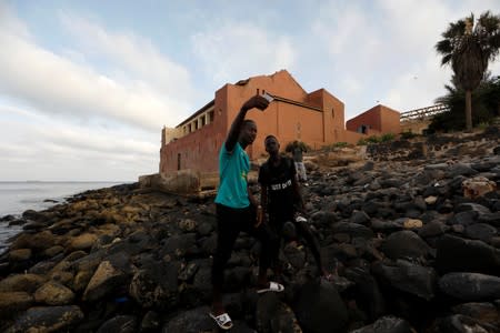 Senegalese tourists take selfies in front of the 'Maison Des Esclaves' slaves house, a gathering point where slaves were shipped west in the 1700s and 1800s, at Goree Island off the coast of Dakar