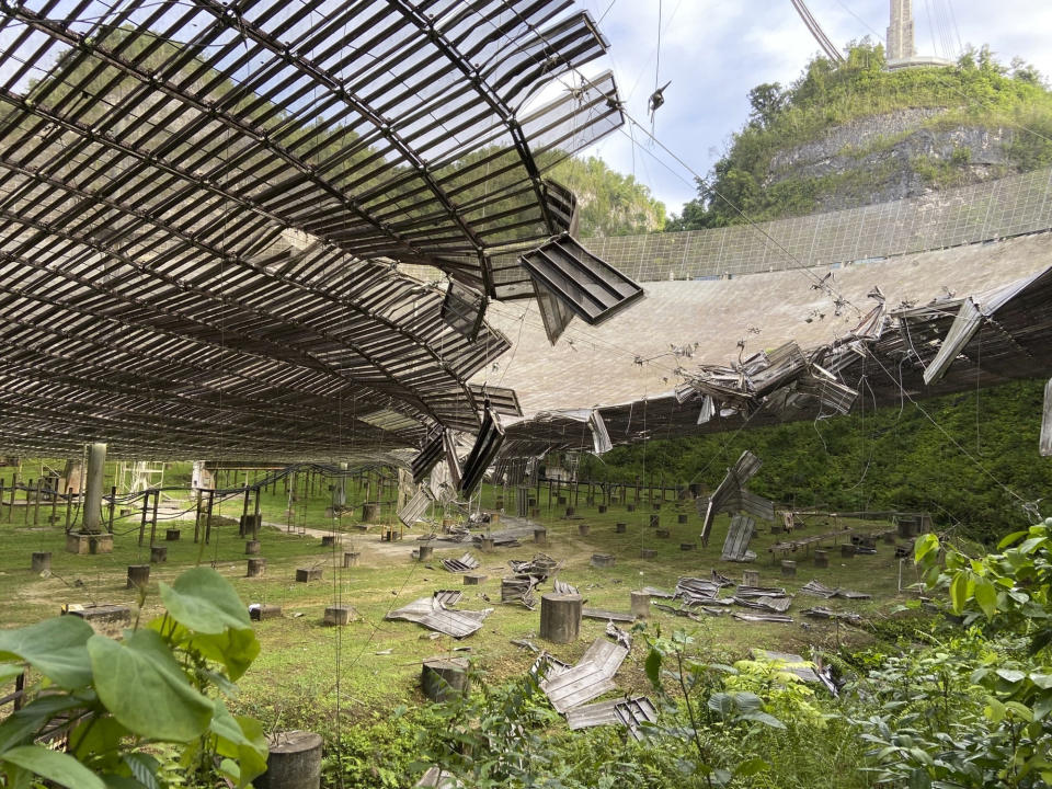 FILE - In this Tuesday, Aug. 11, 2020 file photo, provided by the Arecibo Observatory, shows the damage done by a broken cable that supported a metal platform, creating a 100-foot (30-meter) gash to the radio telescope's reflector dish in Arecibo, Puerto Rico. Giant, aging cables that support the radio telescopes are slowly unraveling in this U.S. territory, threatening scientific projects that researchers say can’t be done elsewhere on the planet. (Arecibo Observatory via AP)