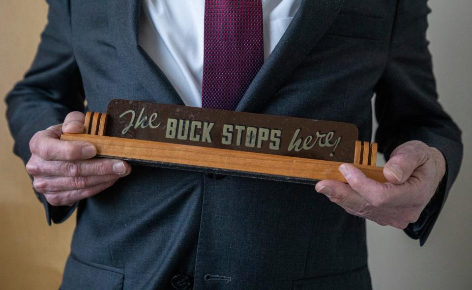 Mayor Jim Fouts holds a desk sign that reads "The Buck Stops Here" as he stands in his office inside City Hall in Warren on Wednesday, Nov. 8, 2023.