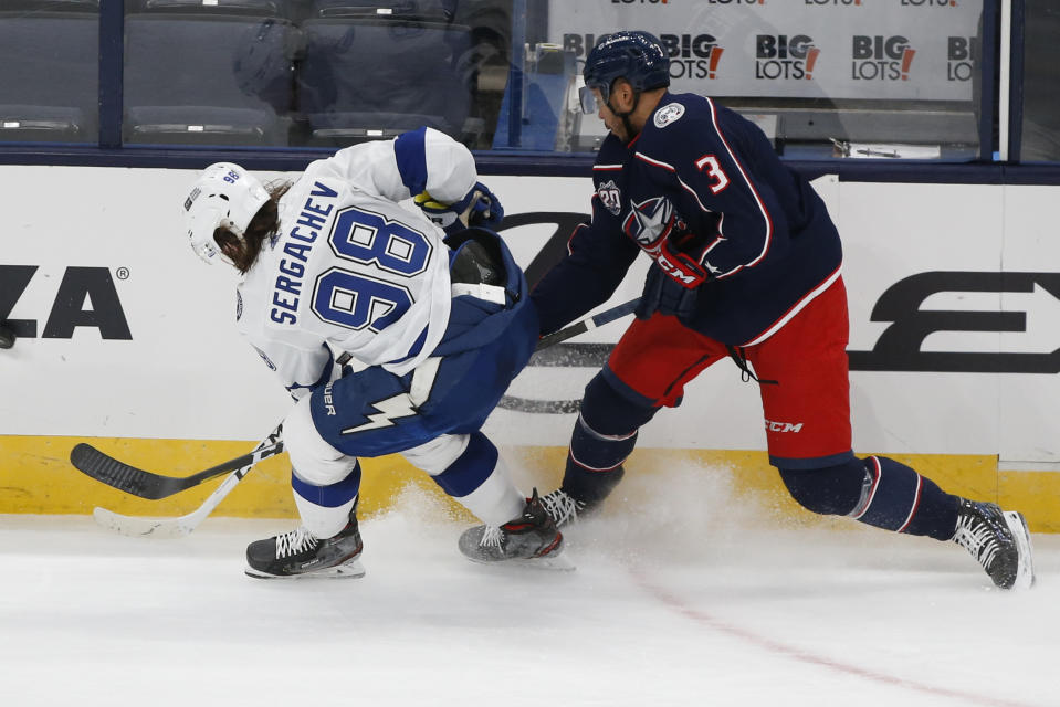 Tampa Bay Lightning's Mikhail Sergachev, left, of Russia, and Columbus Blue Jackets' Seth Jones fight for a loose puck during the third period of an NHL hockey game Saturday, Jan. 23, 2021, in Columbus, Ohio. The Blue Jackets beat the Lightning 5-2. (AP Photo/Jay LaPrete)