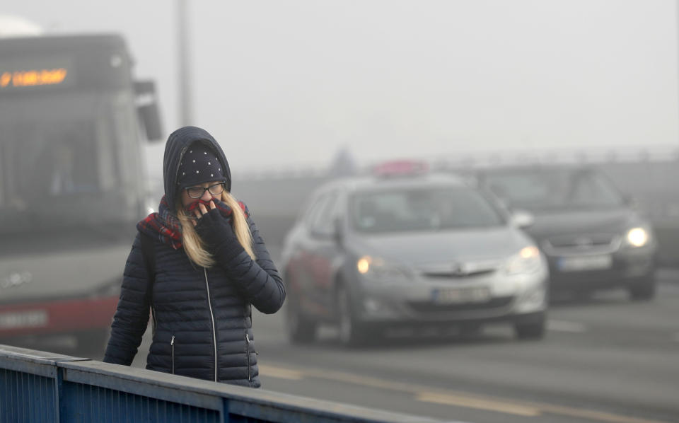 A girl walks across a bridge in Belgrade, Serbia, Wednesday, Jan. 15, 2020. Cities throughout the Balkans have been hit by dangerous levels of air pollution in recent days, prompting residents' anger and government warnings to stay indoors and avoid physical activity. (AP Photo/Darko Vojinovic)