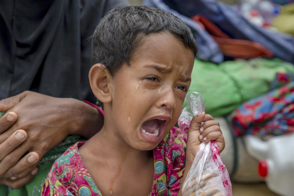 FILE- In this Oct. 20, 2017, file photo, Rohingya Muslim girl Toyiba Khatun cries while fighting fever as she waits with her family to be registered which will then allow them to proceed to build a shelter in Kutupalong refugee camp, Bangladesh. A new report by the United Nations children’s agency says the lives and futures of more than 19 million Bangladeshi children are at risk from colossal impacts of devastating floods, cyclones and other environmental disasters linked to climate change. The UNICEF report released Friday, April 5, 2019, said the tally includes Rohingya refugee children from Myanmar who are living in squalid camps in southern Bangladesh. (AP Photo/Dar Yasin, File)