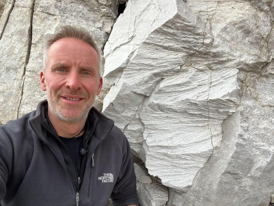 Gordon Osinski pictured at the Haughton impact structure in Nunavut. The rocks behind him with grooves are an example of shatter cones, which represent definitive proof of a crater.