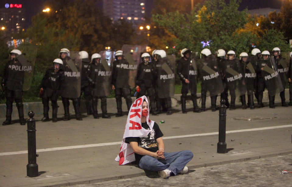 A lone Polish fan sits in front of a line of riot police.