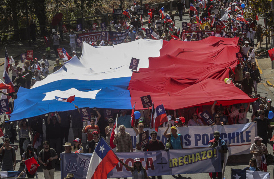 Un grupo numeroso de manifestantes marcha con la bandera chilena durante una protesta contra la creación de una nueva Constitución que reemplazaría la Carta Magna heredada de la dictadura de Augusto Pinochet, en Santiago de Chile, el sábado 22 de febrero de 2020. (AP Foto/Esteban Félix)