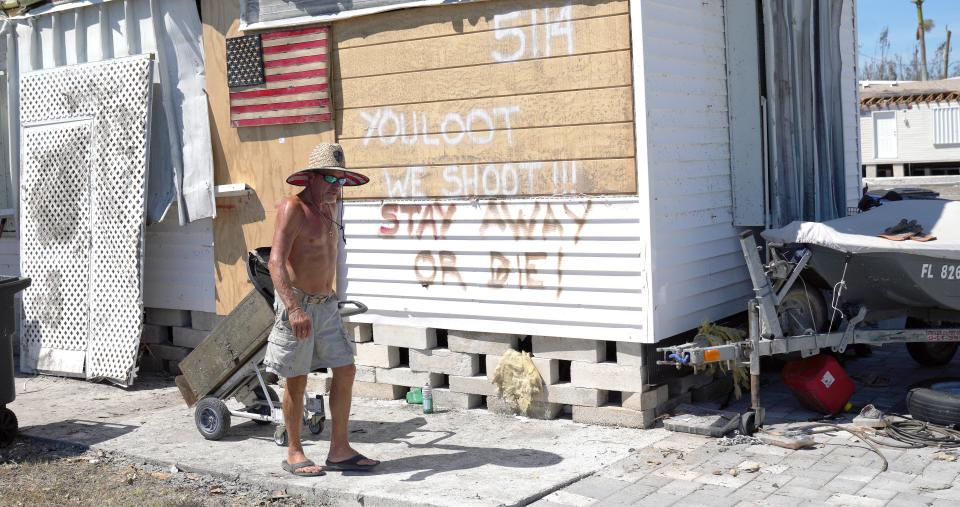 Curtis Eggleston carries some of his belongings out of his hurricane-damaged home on Pine Island, Fla., on Monday.