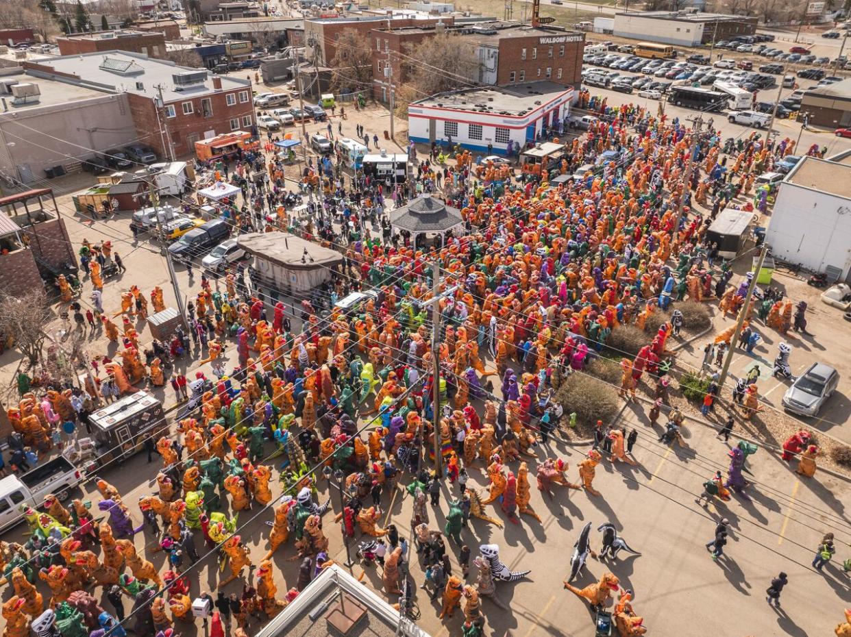 Thousands of people stomp into Drumheller in an attempt to break the Guiness World Record for the largest gathering of people dressed in dinosaur costumes. (Travel Drumheller - image credit)