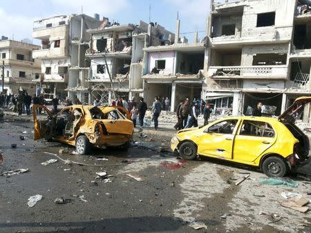 Syrian army soldiers and civilians inspect the site of a two bomb blasts in the government-controlled city of Homs, Syria, in this handout picture provided by SANA on February 21, 2016. REUTERS/SANA/Handout via Reuters