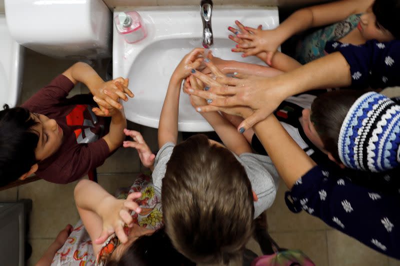 Teacher shows children how to wash their hands at her kindergarten in Jerusalem