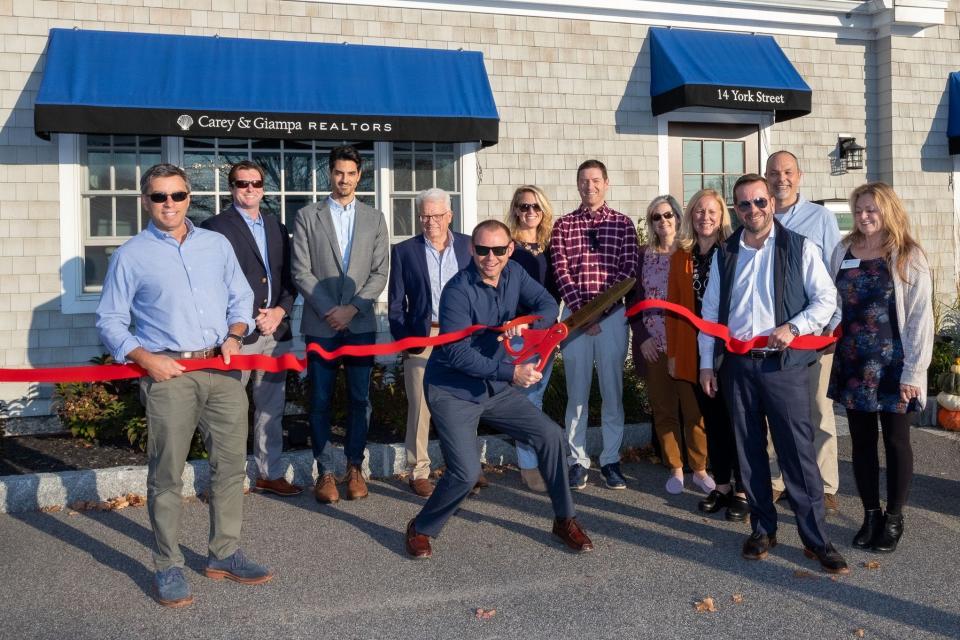 Carey and Giampa Realtors celebrate the opening of their fifth office in York, Maine with a ribbon cutting. From left to right are: Jim Giampa, Patrick Doherty, Nick Ponte, Fritz Schermer, Sara Walenta, Matt Sukeforth, Chalise Magill, Tamara Millard, Mike Millard, Patrick Carey, Holly Roberts, executive director, York Region Chamber of Commerce; at center of photo Kevin Erikson.