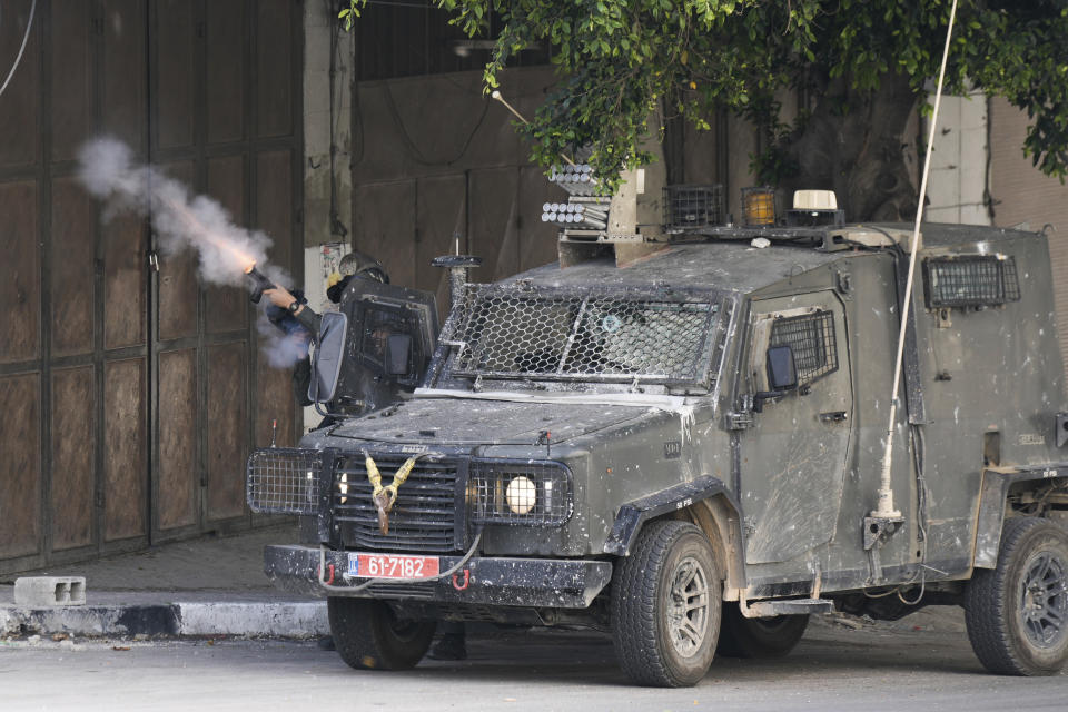 An Israeli border police officer fires tear gas towards Palestinian protesters during an Israeli army raid in the Balata refugee camp near the West Bank town of Nablus, Saturday, May 13, 2023. The Israeli military raided the Balata refugee camp in the northern city of Nablus, sparking a firefight that killed two Palestinians. (AP Photo/Majdi Mohammed)