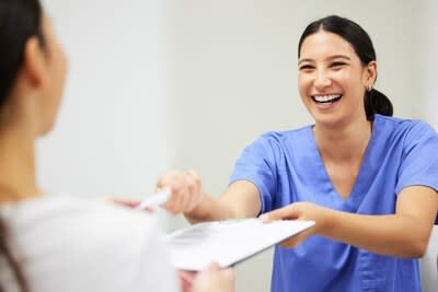 A dental receptionist hands a patient a form. (CNW Group/Ontario Dental Assistants Association)