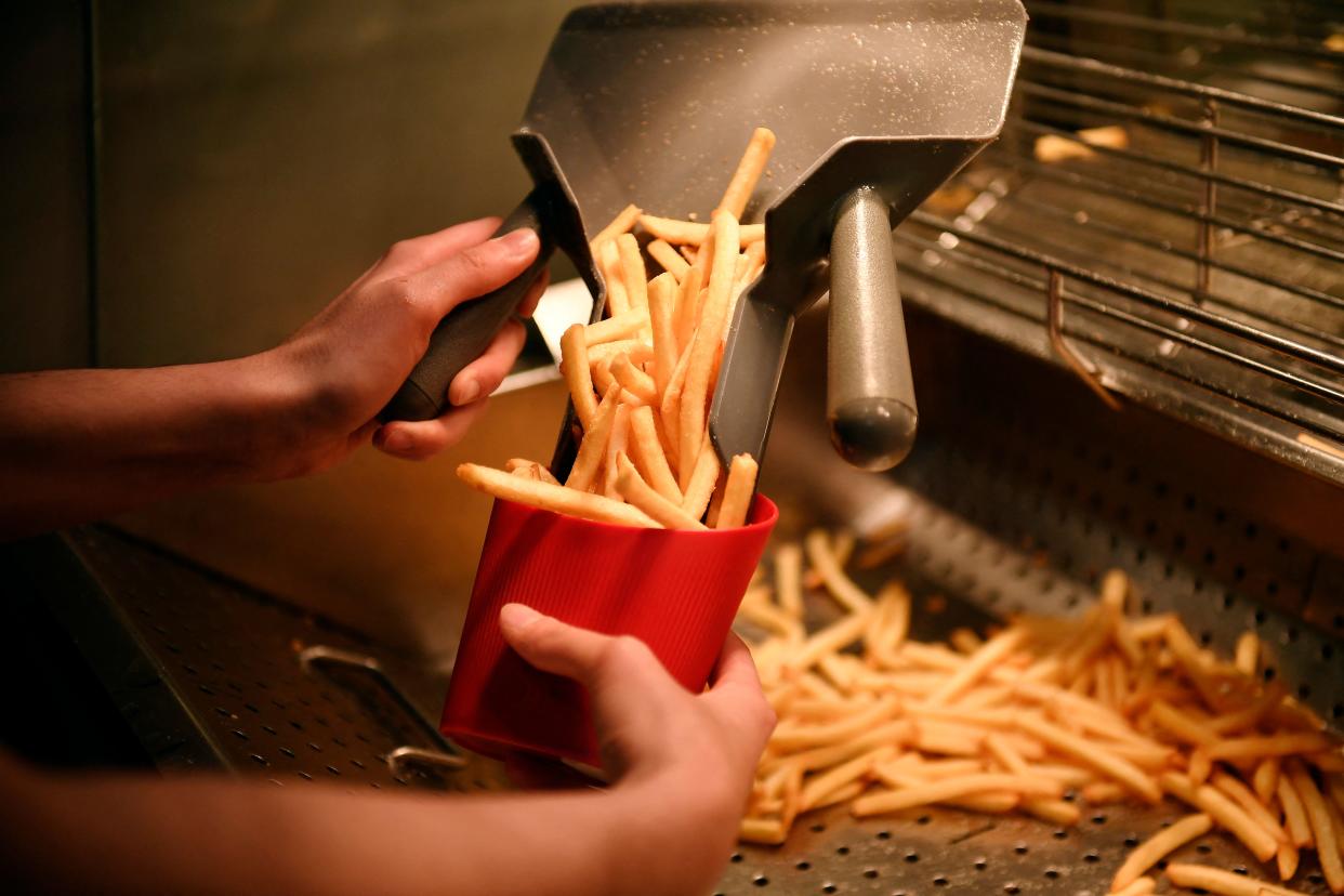 An employee serves french fries in a reusable container at a McDonald's restaurant in Levallois-Perret, near Paris, on December 20, 2022. - From January 1, 2023, within the framework of the anti-waste law, fast food restaurants must use reusable dishes for on-site orders. (Photo by JULIEN DE ROSA / AFP) (Photo by JULIEN DE ROSA/AFP via Getty Images)