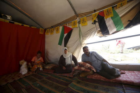 Palestinian man Jihad Nuwaja sits with his family inside his tent in Susiya village, south of the West Bank city of Hebron July 20, 2015. REUTERS/Mussa Qawasma