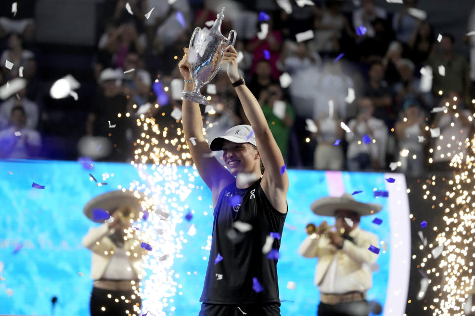 Iga Swiatek, of Poland, holds up her trophy after her victory over Jessica Pegula, of the United States, in the women's singles final of the WTA Finals tennis championships, in Cancun, Mexico, Monday, Nov. 6, 2023. (AP Photo/Fernando Llano)