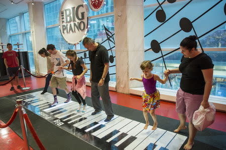 Tourists play on the "Big" piano inside of the toy store FAO Schwarz on the last day that the store will be open in New York, July 15, 2015. REUTERS/Lucas Jackson