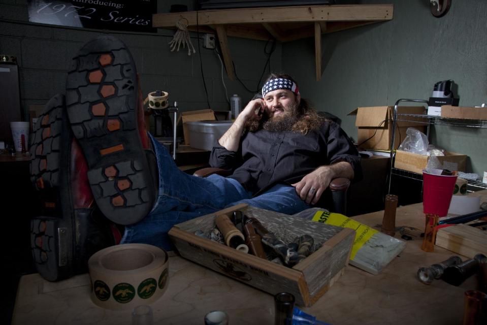 This undated photo provided by A&E, shows Willie Robertson, star of A&E’s “Duck Dynasty,” at his desk in his office at the Duck Commander warehouse in West Monroe, La. Turning small business owners into stars has become a winning formula for television producers, but some businesses featured in them are cashing in, too. Sales explode after just a few episodes air, transforming these nearly unknown small businesses into household names. In addition to earning a salary from starring in the shows, some small business owners are benefiting financially from opening gift shops that sell souvenirs or getting involved in other ventures that spawn from their new-found fame. (AP Photo/A&E)