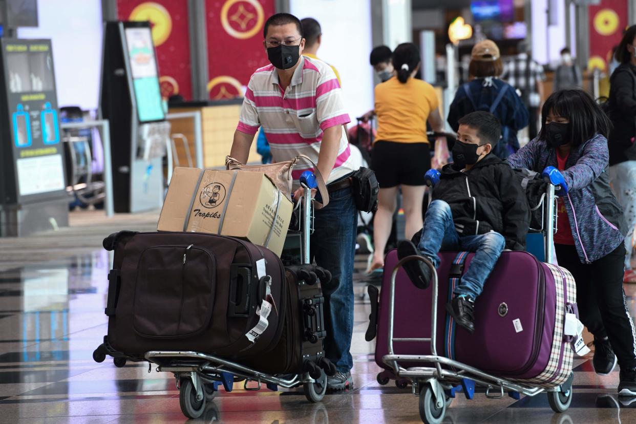 Travellers wear protective facemasks at the departure hall of Changi Airport on 30 January, 2020. (PHOTO: AFP via Getty Images)