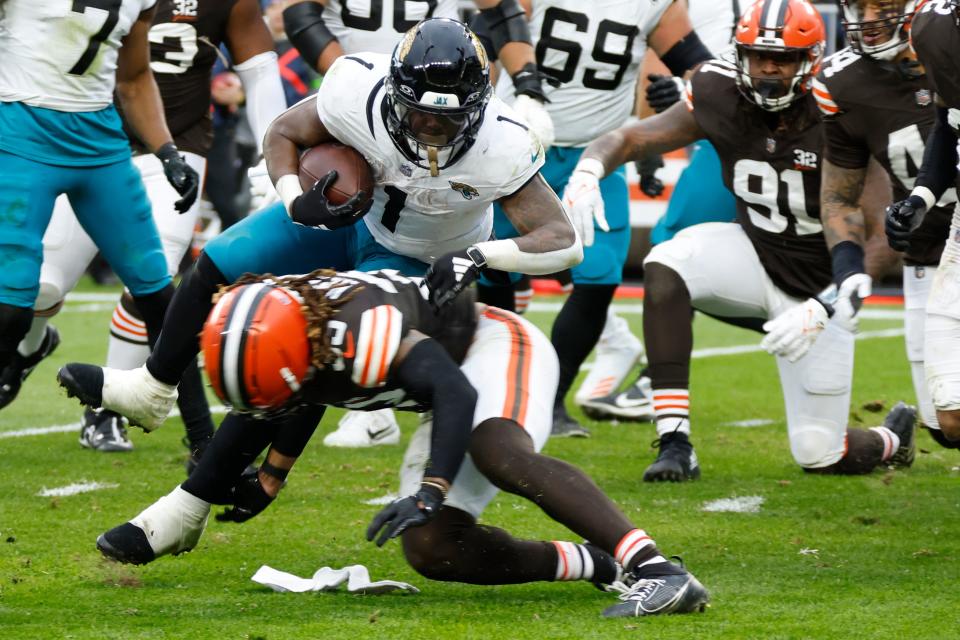 Jacksonville Jaguars running back Travis Etienne Jr. (1) jumps over Cleveland Browns safety Ronnie Hickman during the second half Sunday in Cleveland.
