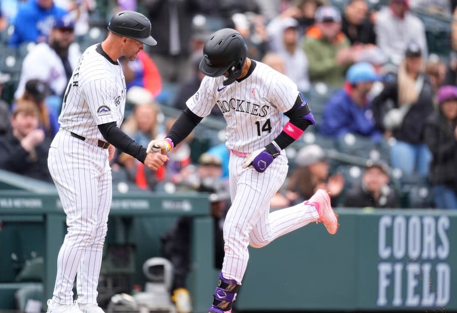 Colorado Rockies third base coach Warren Schaeffer, left, congratulates Ezequiel Tovar, right, who circles the bases after hitting a two-run home run off Texas Rangers starting pitcher José Ureña in the first inning of a baseball game Sunday, May 12, 2024, in Denver. (AP Photo/David Zalubowski)