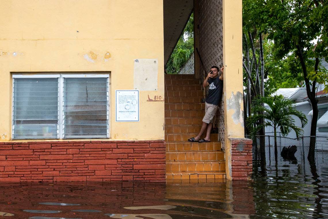 A man records the floodwaters as he stays dry atop the stairs off Southwest Third Street and Eighth Avenue in the Little Havana neighborhood of Miami, Florida, on Saturday, June 4, 2022.