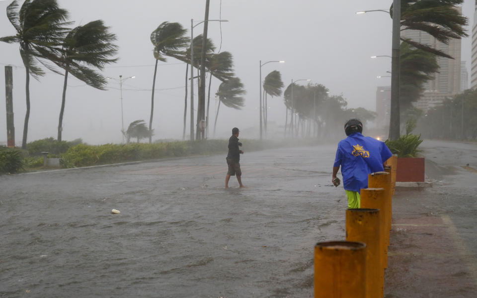 A commuter braves the rain and strong winds brought about by Typhoon Mangkhut which barreled into northeastern Philippines before dawn Saturday, Sept. 15, 2018 in Manila, Philippines. The typhoon slammed into the Philippines' northeastern coast early Saturday, its ferocious winds and blinding rain ripping off tin roof sheets and knocking out power, and plowed through the agricultural region at the start of the onslaught. (AP Photo/Bullit Marquez)