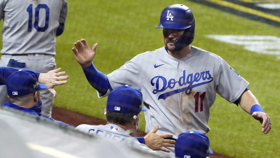 Los Angeles Dodgers' A.J. Pollock (11) is congratulated after scoring on a sacrifice fly by Mookie Betts against the San Diego Padres during the fifth inning in Game 3 of a baseball National League Division Series Thursday, Oct. 8, 2020, in Arlington, Texas. (AP Photo/Sue Ogrocki)