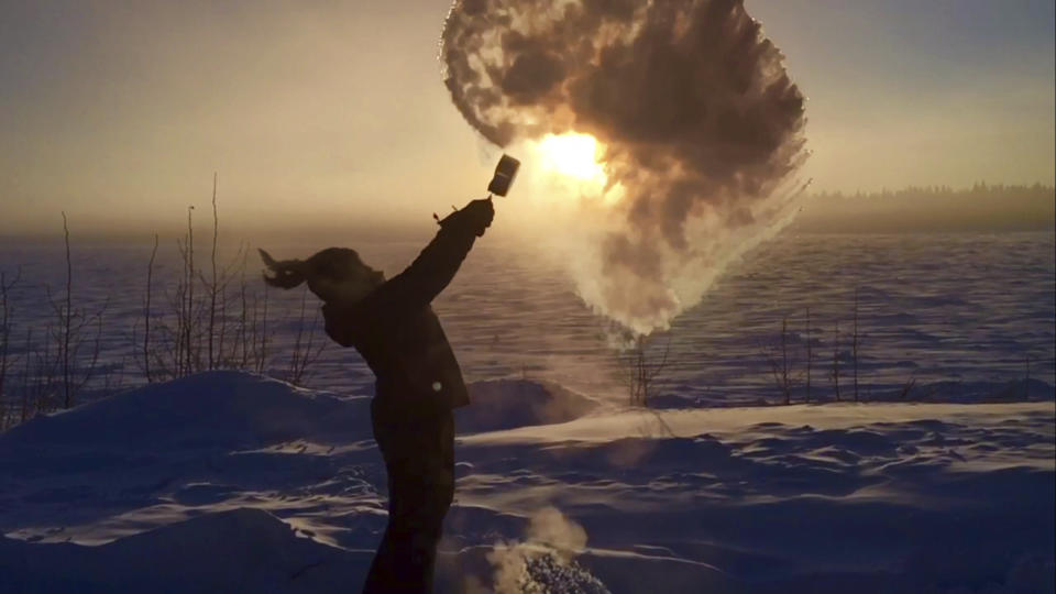 Ice crystals shower down on Courtney Moore Agnes after she flung a pot of boiling water into the air Wednesday, Jan. 18, 2017, in Tanana, Alaska. The temperature Wednesday at the Tanana airport reached 54 below zero Fahrenheit (-48 Celsius), the coldest recorded in the state, and was 5 degrees colder at -59 F (-51 C) along the river. (Cynthia Erickson via AP)