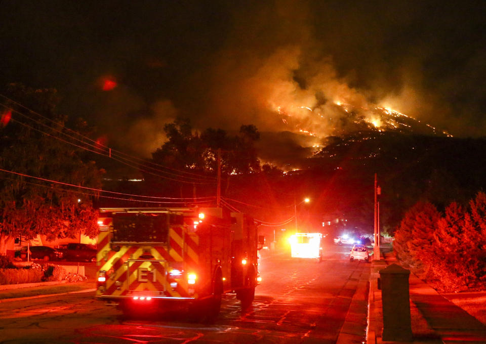 Fire crews head up East Pages Lane as a fire burns on the hill East of Centerville, Utah early Friday, Aug. 30, 2019. Three homes were destroyed and anther eight were impacted with fire damage. An additional 400 homes have been evacuated in the Centerville area. (Colter Peterson/The Deseret News via AP)