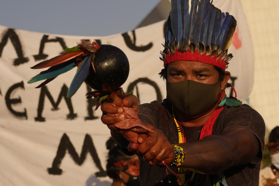 An Indigenous man performs a ritual during the "Luta pela Vida," or Struggle for Life mobilization, a protest to pressure Supreme Court justices who are expected to issue a ruling that will have far-reaching implications for tribal land rights, outside the Supreme Court in Brasilia, Brazil, Wednesday, Aug. 25, 2021. (AP Photo/Eraldo Peres)