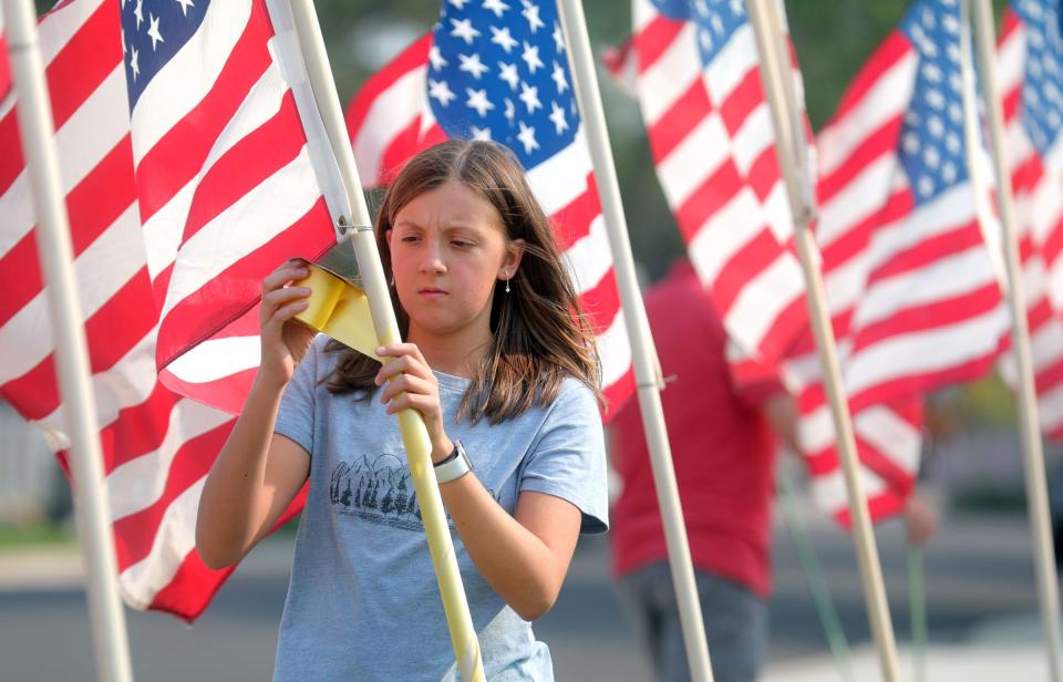 Neighbor Cora McIllece puts up flags around the house belonging to the father of U.S. Marine Staff Sgt. Darin Taylor Hoover Jr. in Sandy on Friday, Aug. 27, 2021. Hoover Jr. was killed in the suicide bombing at the Kabul Airport in Afghanistan. | Kristin Murphy, Deseret News