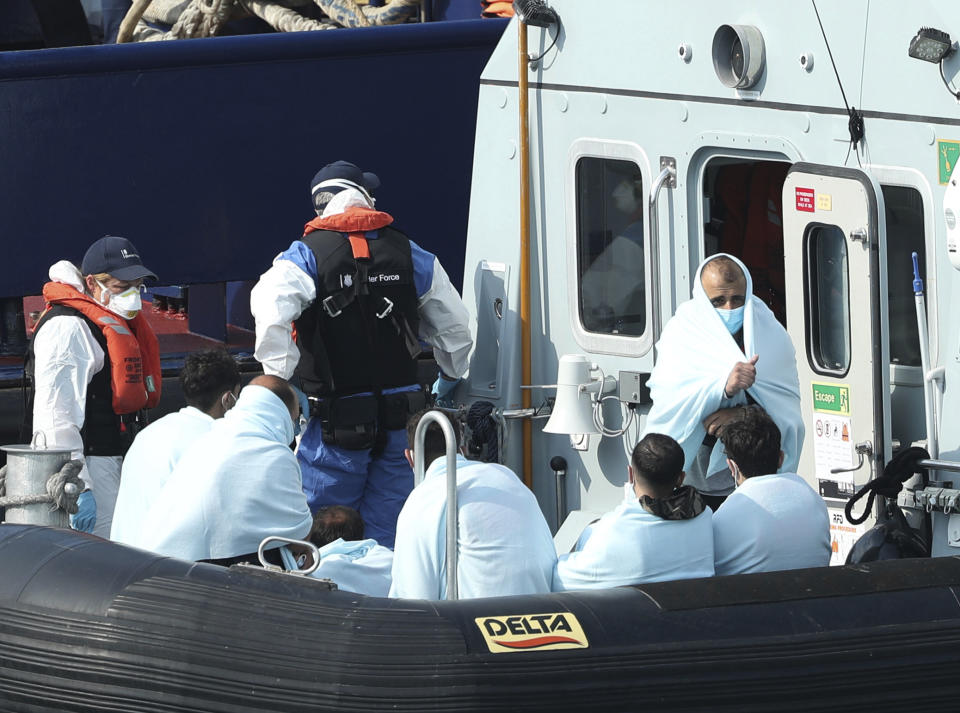 A Border Force vessel brings a group of people thought to be migrants into the port city of Dover, southern England, Sunday Aug. 9, 2020. Many migrants have used small craft during the recent hot calm weather to make the dangerous journey from northern France, to cross the busy shipping lanes of The Channel to reach Britain. (Yui Mok/PA via AP)