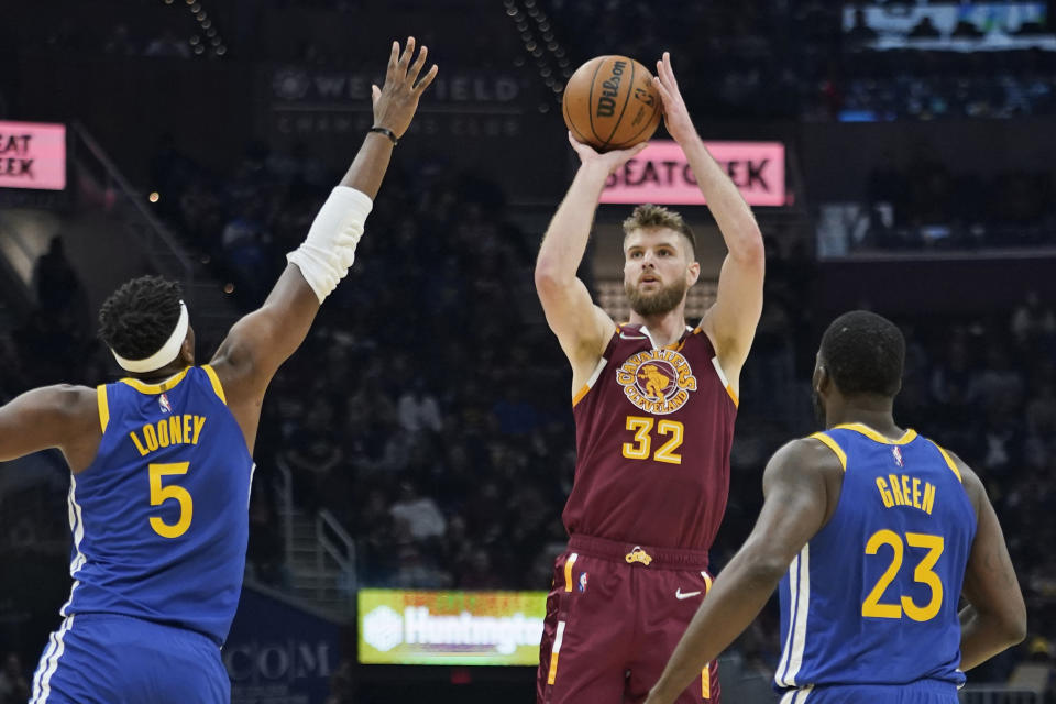 Cleveland Cavaliers' Dean Wade (32) shoots against Golden State Warriors' Kevon Looney (5) and Draymond Green (23) in the first half of an NBA basketball game, Thursday, Nov. 18, 2021, in Cleveland. (AP Photo/Tony Dejak)