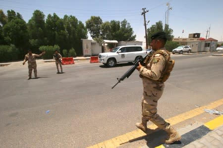 Iraqi soldiers stay guard at the entry of Zubair oilfield after a rocket struck the site of residential and operations headquarters of several oil companies in Basra